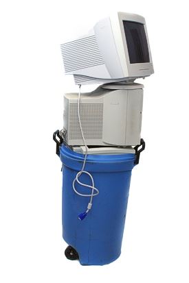 A stack of old computer monitors on a trash can